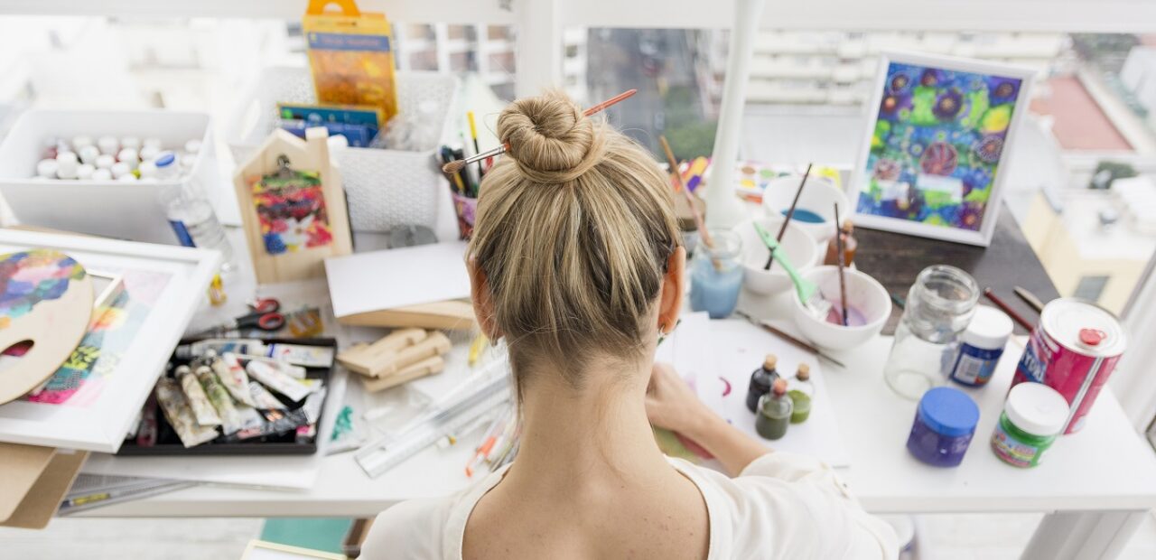 woman on a table with a lot of art and craft materials