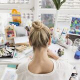 woman on a table with a lot of art and craft materials