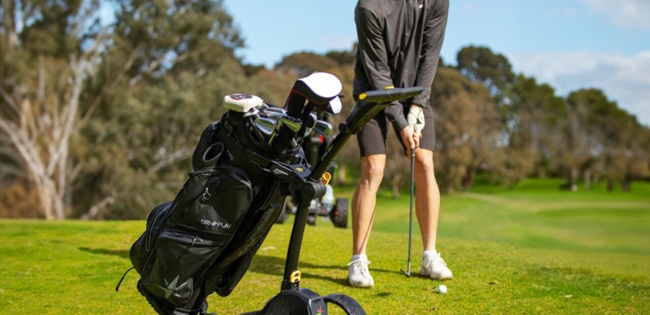 a person playing golf next to a motorised golf buggy