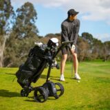 a person playing golf next to a motorised golf buggy