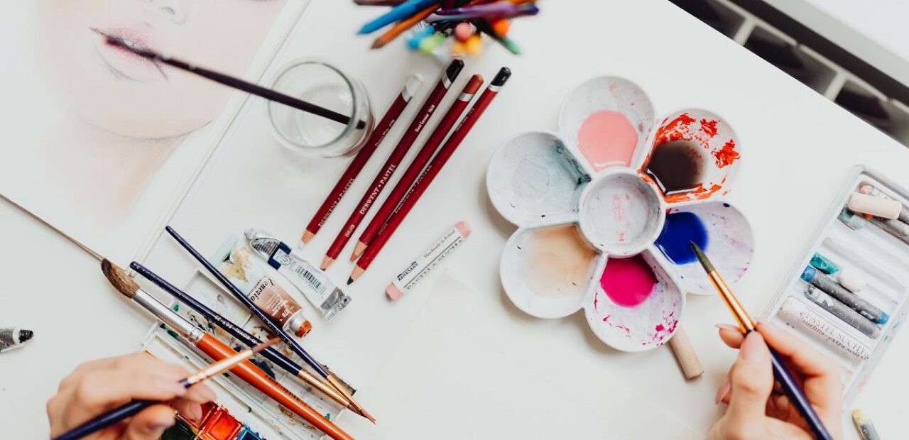 person painting with watercolour paints and pencils